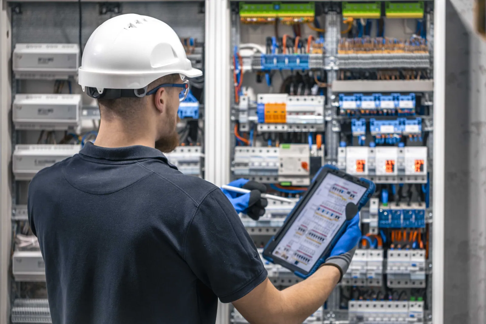 Electricista con casco revisando un cuadro eléctrico con una tableta para emitir un certificado CIE en Gran Canaria