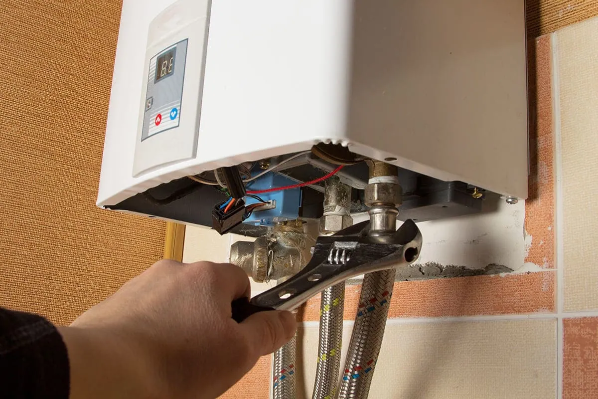 Técnico ajustando las tomas de agua y gas de un calentador de gas en una vivienda de Tenerife