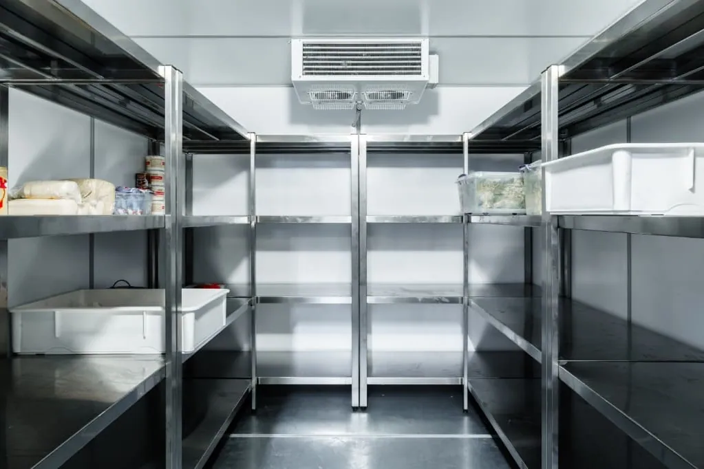 Interior de una cámara frigorífica con estanterías y pasillo libre para que circule el aire frío