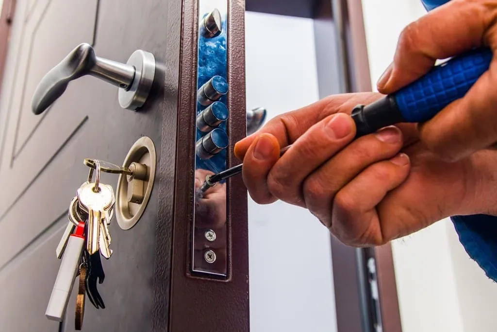 Cerrajero con un juego de llaves trabajando en la cerradura de una puerta
