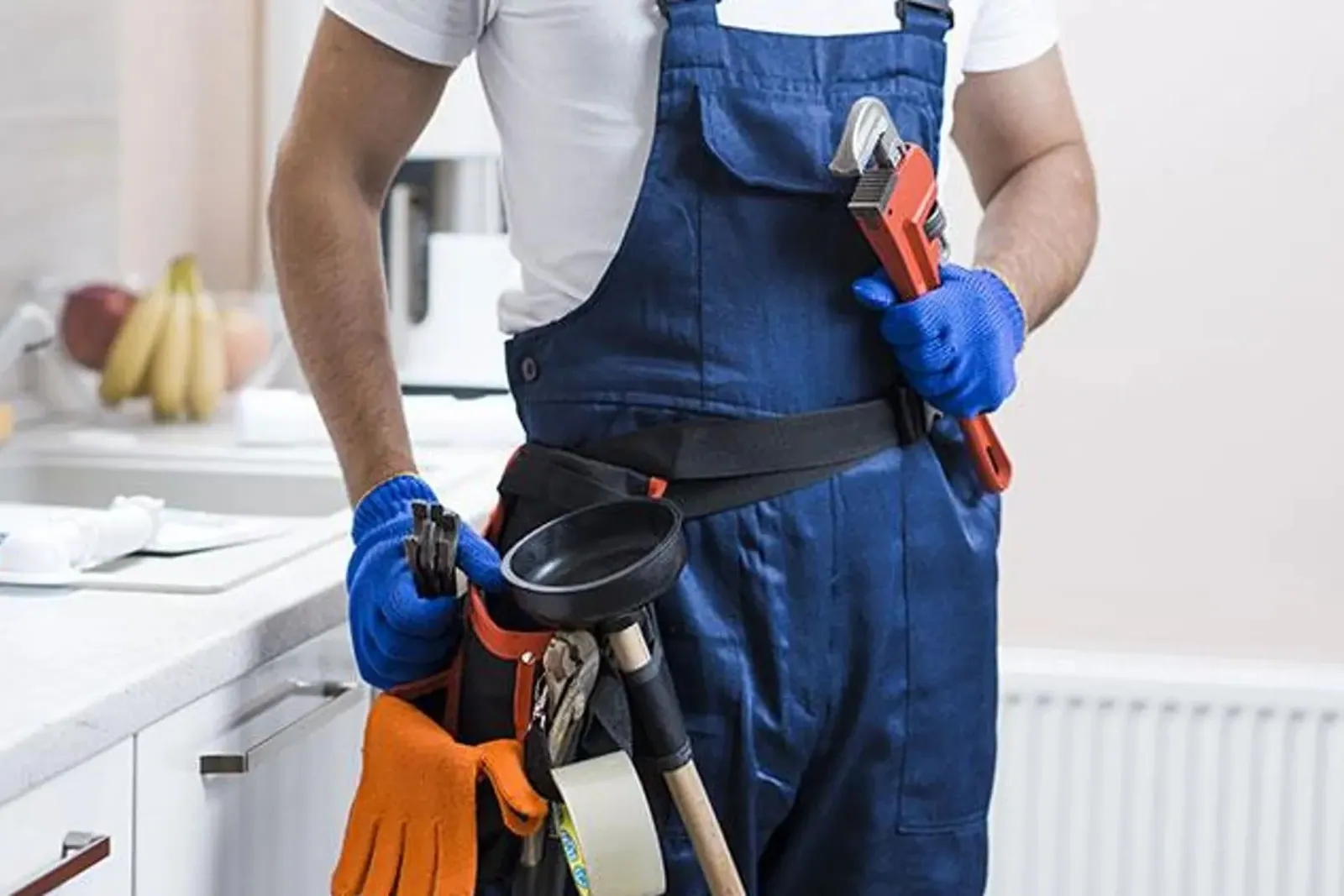 Profesional con cinturón de herramientas en una cocina antes de revisar un desagüe atascado en Tenerife
