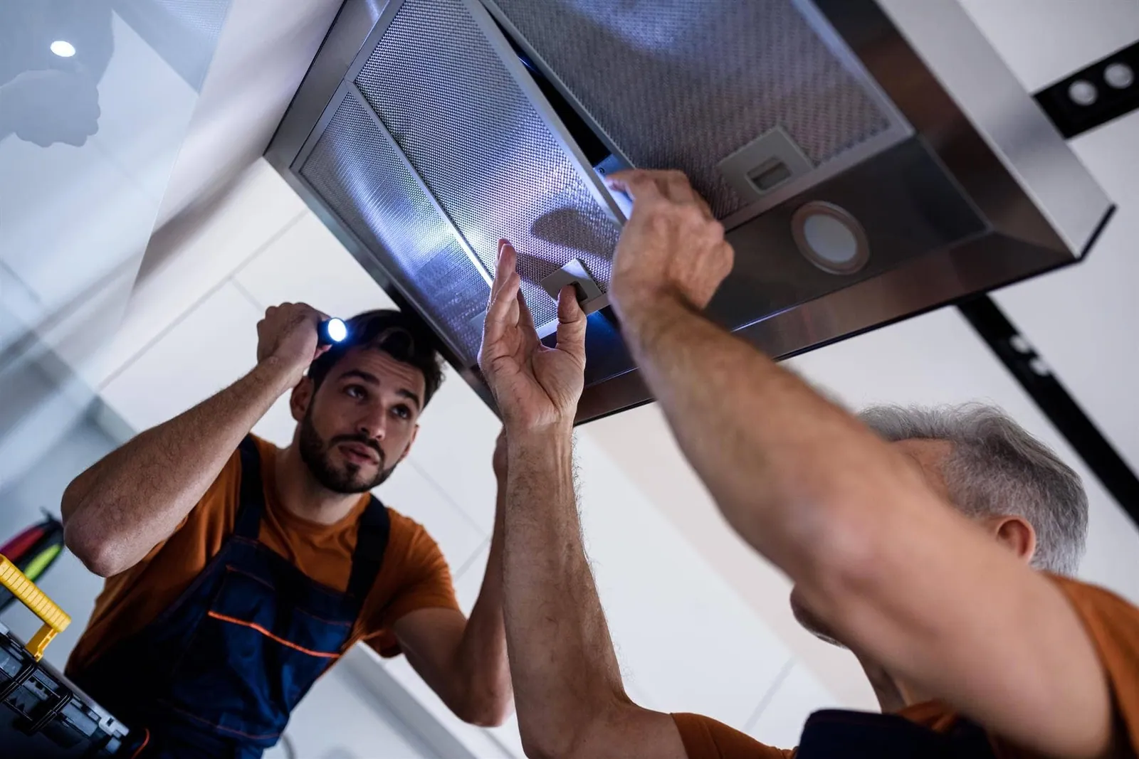 Técnicos montando una campana extractora en la pared de una cocina durante su instalación