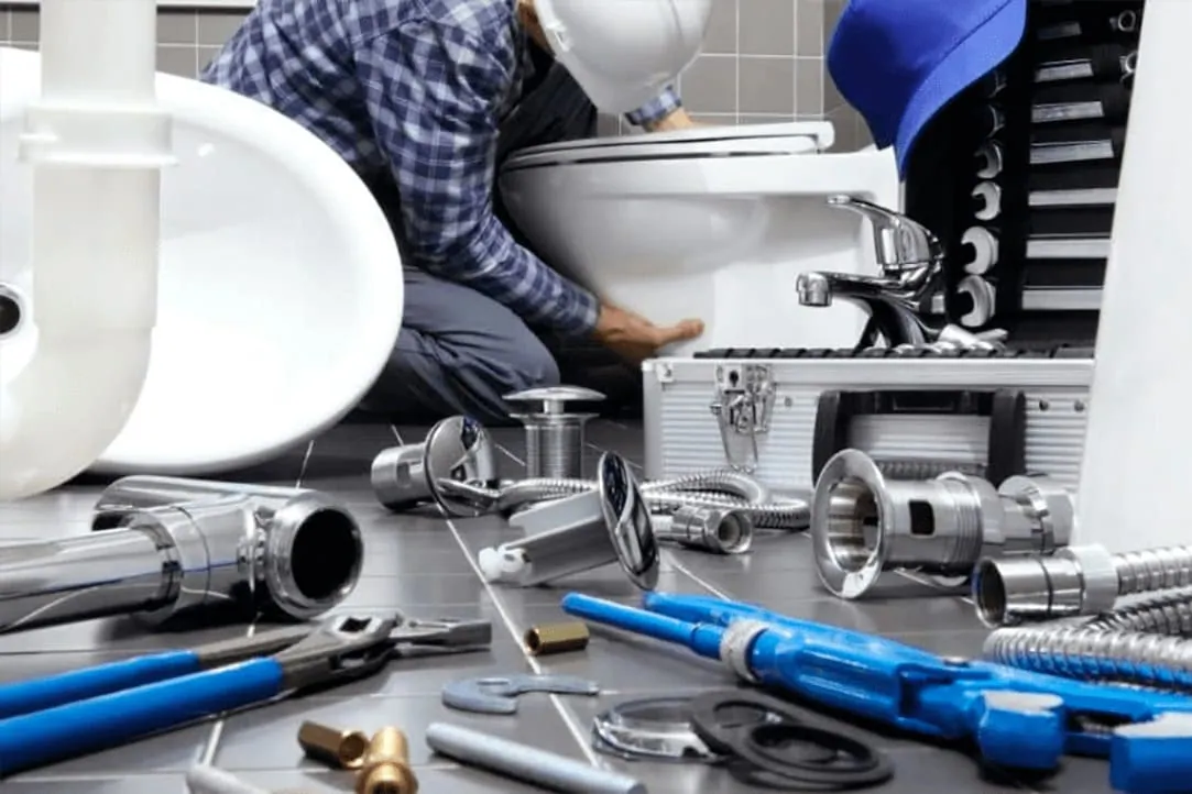 Herramientas y racores de fontanería junto a un lavabo, preparados para una reparación