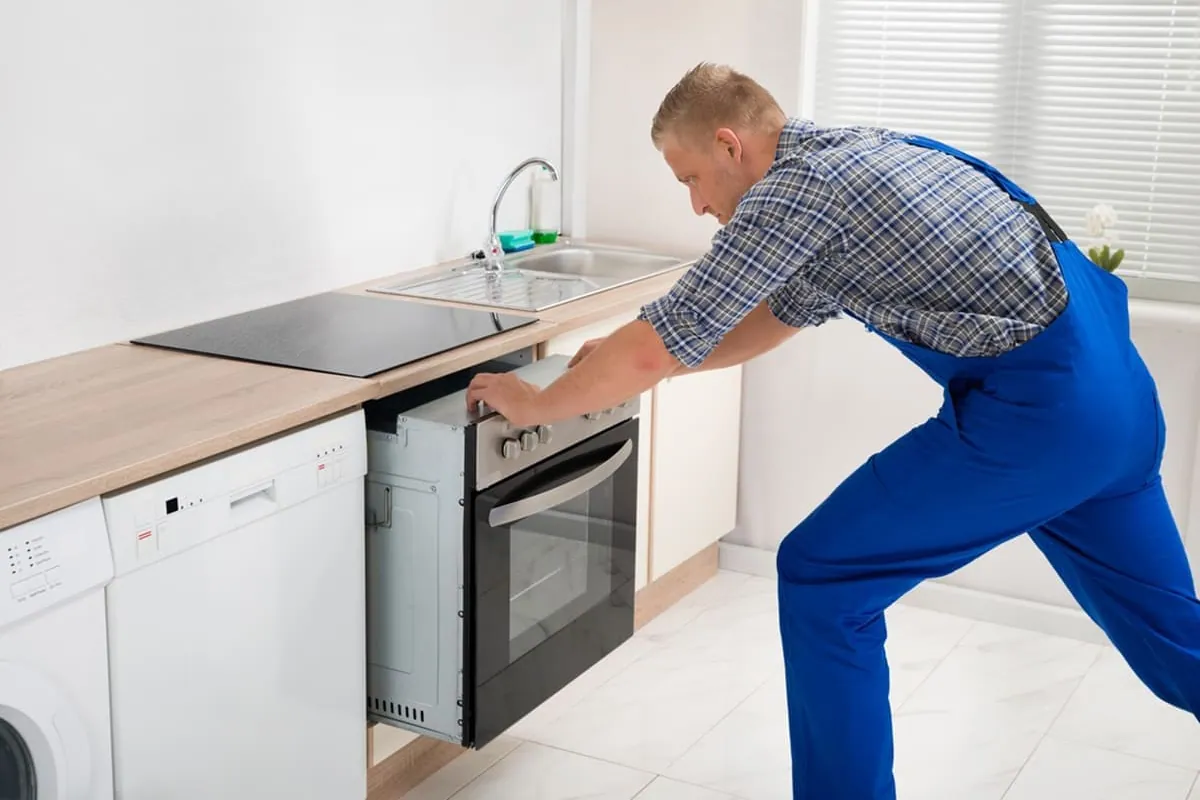 Técnico instalando un horno bajo encimera, trabajo incluido en la instalación de hornos