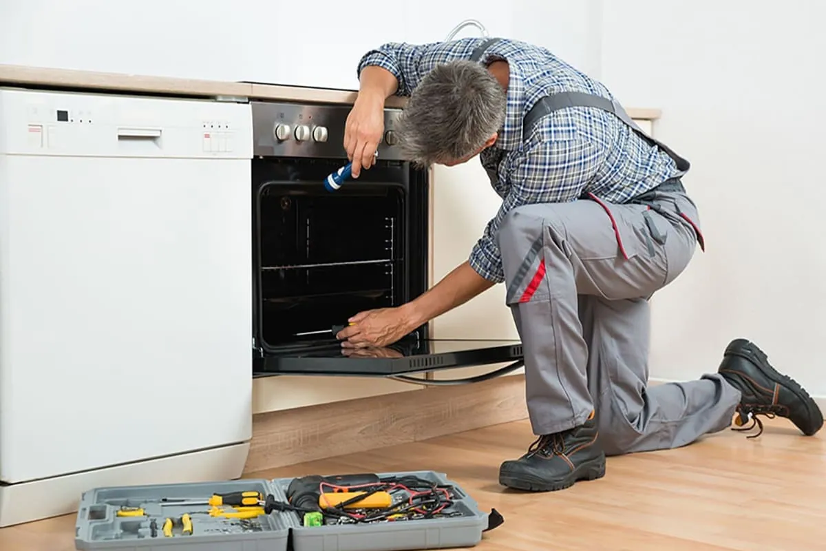 Técnico reparando un horno durante una visita de servicio técnico a domicilio