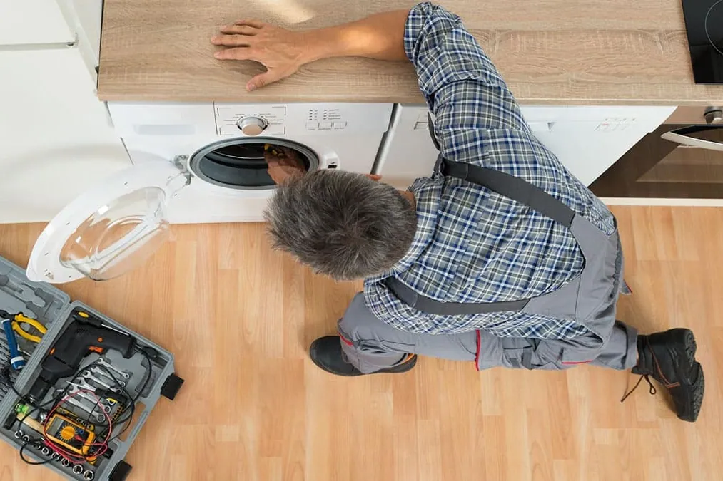 Técnico instalando una lavadora bajo la encimera de una cocina en Tenerife