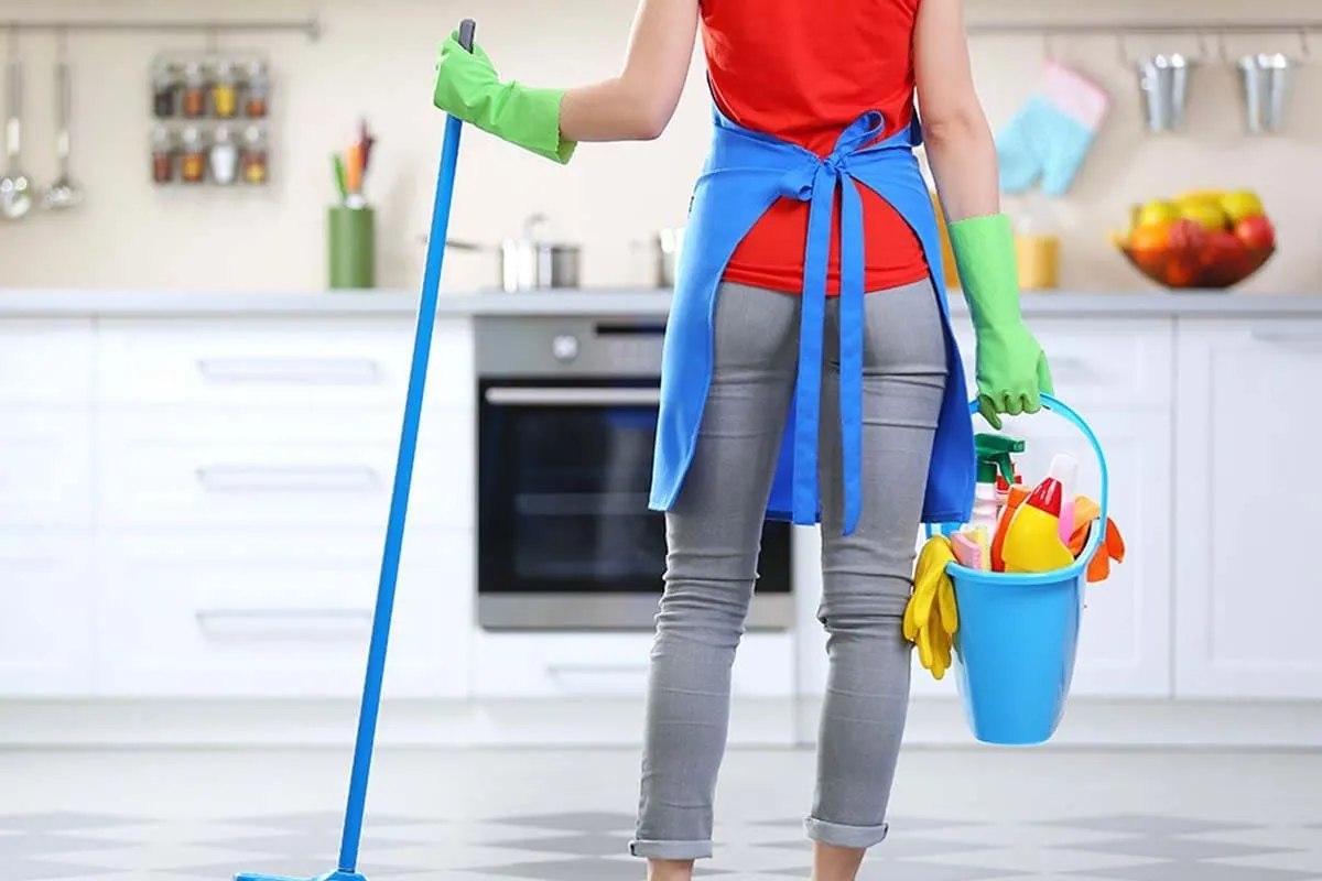Persona con escoba y cubo limpiando una cocina durante un servicio de limpieza en Tenerife
