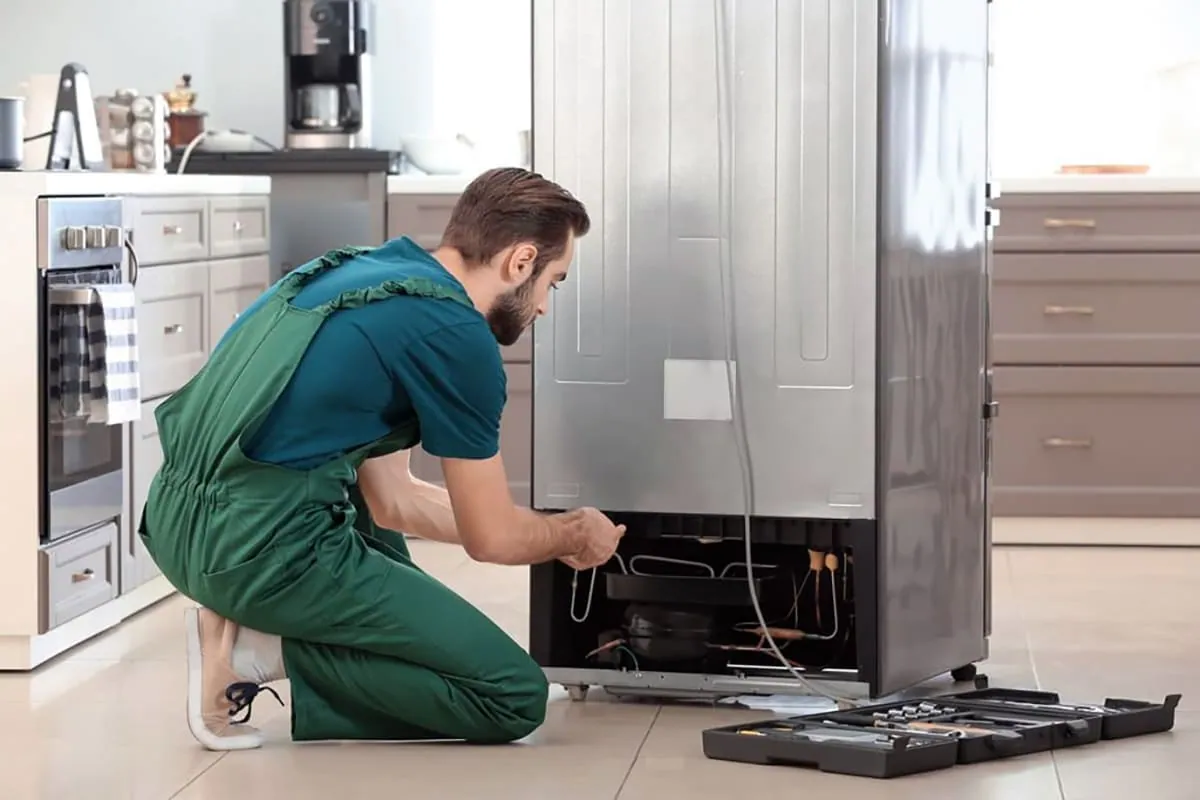 Técnico revisando la parte trasera de un frigorífico durante una reparación en Tenerife