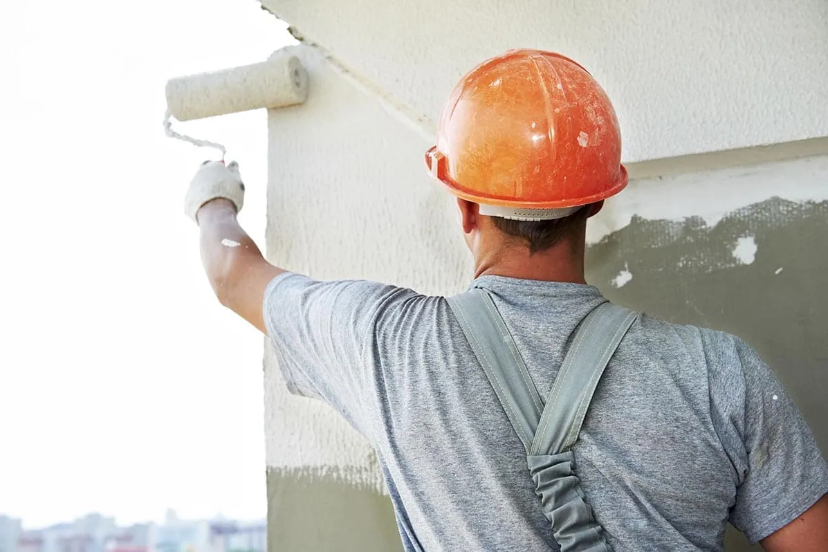 Pintores en Tenerife: pintor con casco pintando la fachada de un edificio