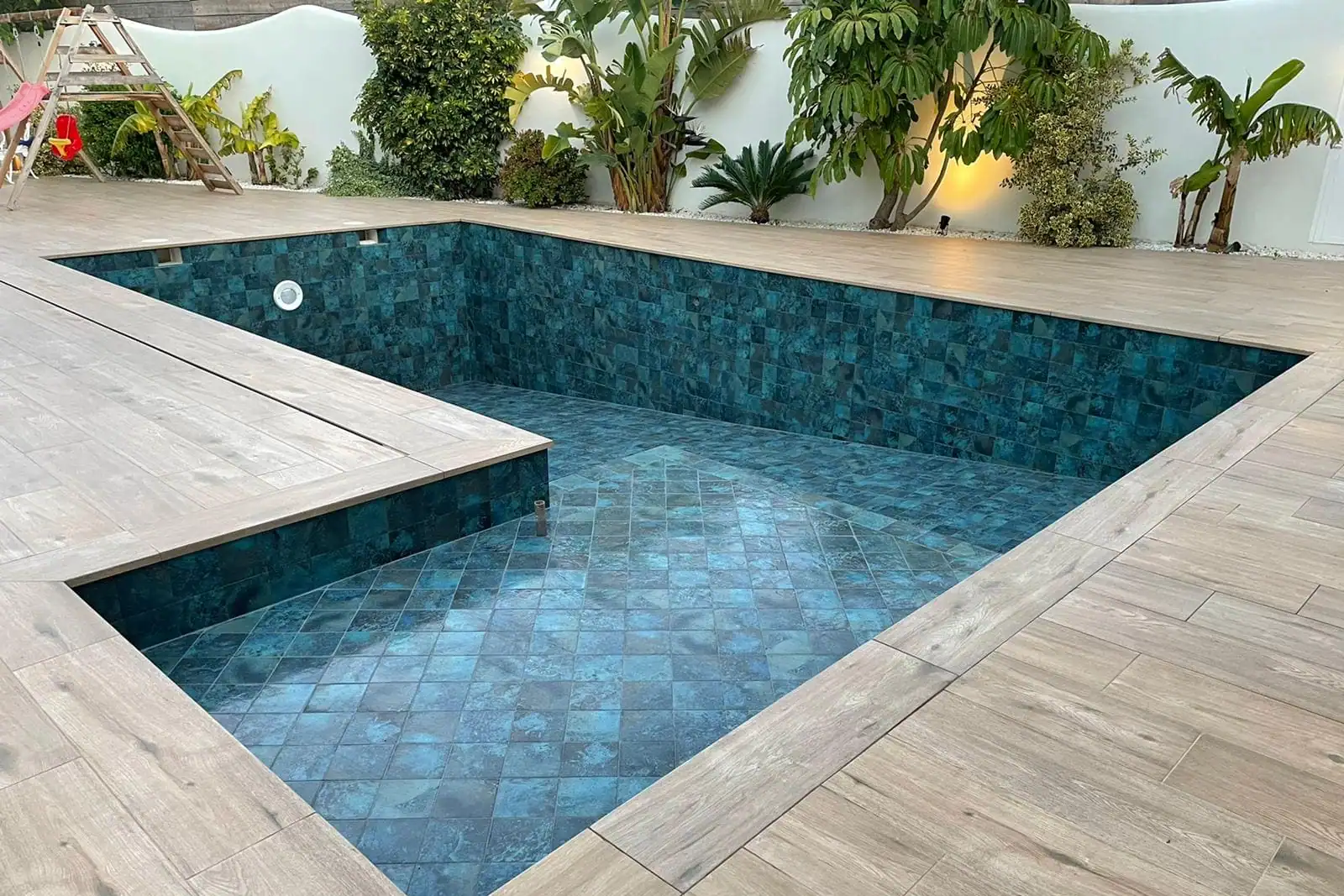 Piscina pequeña revestida de gresite con tarima de madera alrededor