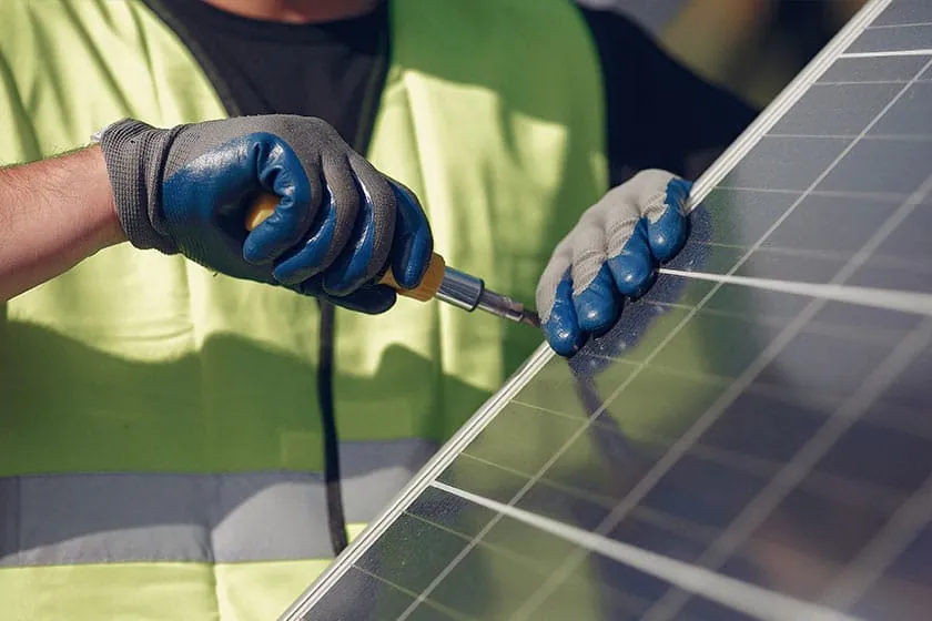 Instalación de placas solares en Tenerife: operario con guantes de trabajo fijando un panel solar a su estructura