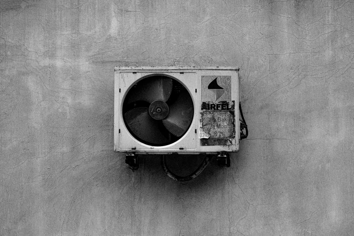 Aire acondicionado colgado en una pared de hormigón en blanco y negro