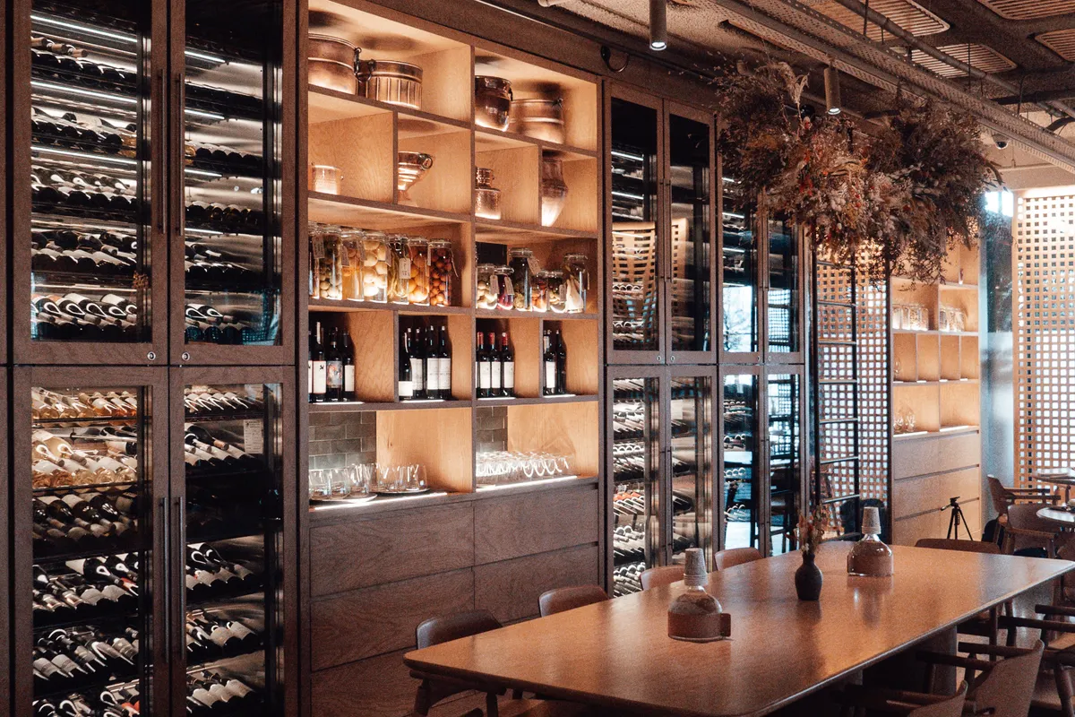 Armarios climatizados para vino con puertas de cristal, luz interior y botellas tumbadas en un restaurante