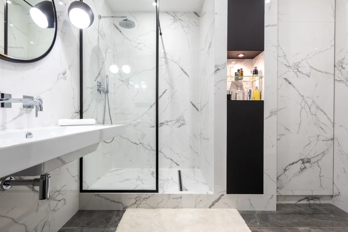 Baño moderno con ducha, lavabo y espejo que refleja la mampara