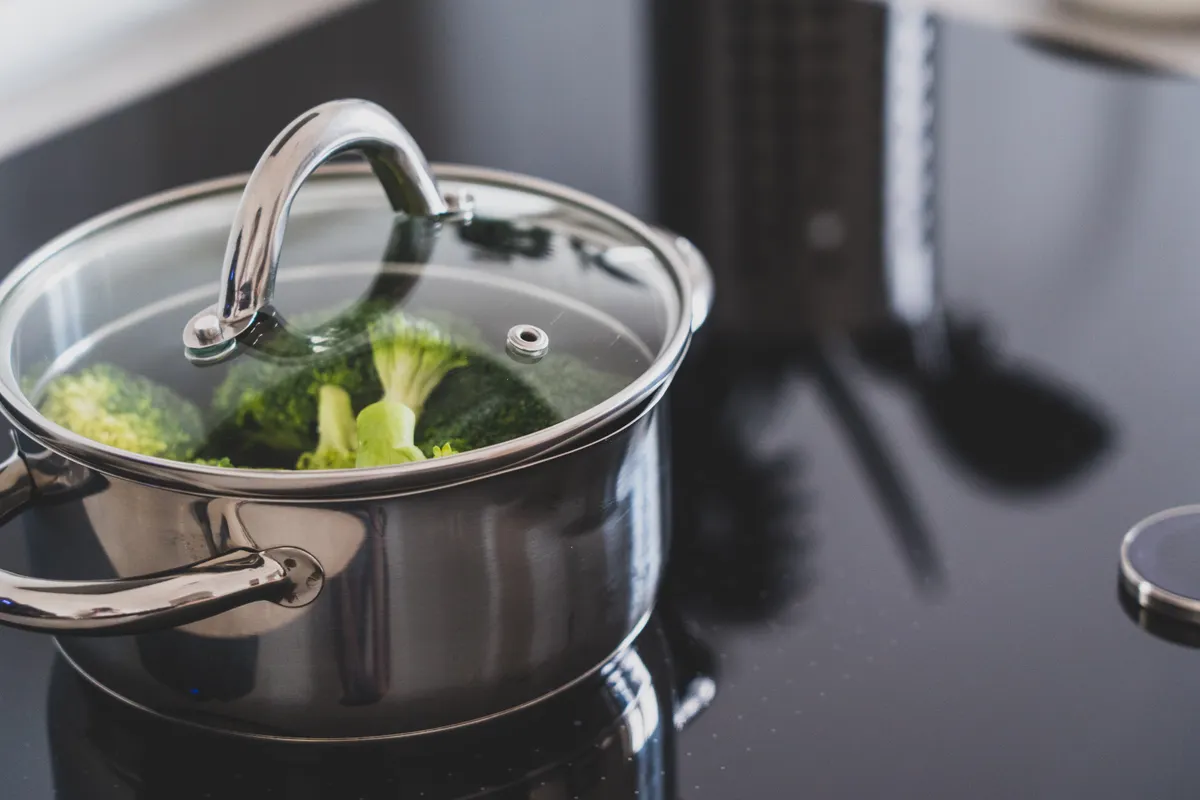 Brócoli cociéndose al vapor en una olla de acero inoxidable sobre una placa moderna