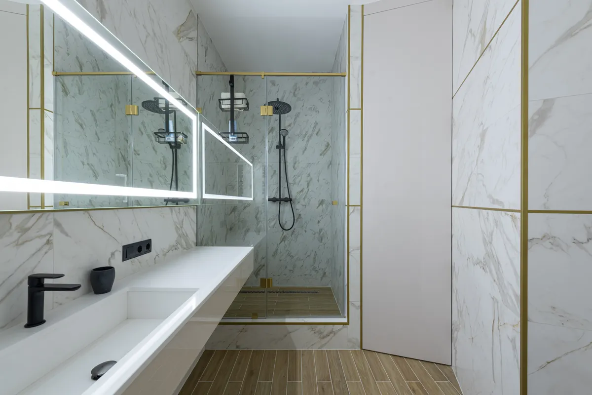 Cabina de ducha y lavabo de cerámica en un baño de mármol con gran ventana