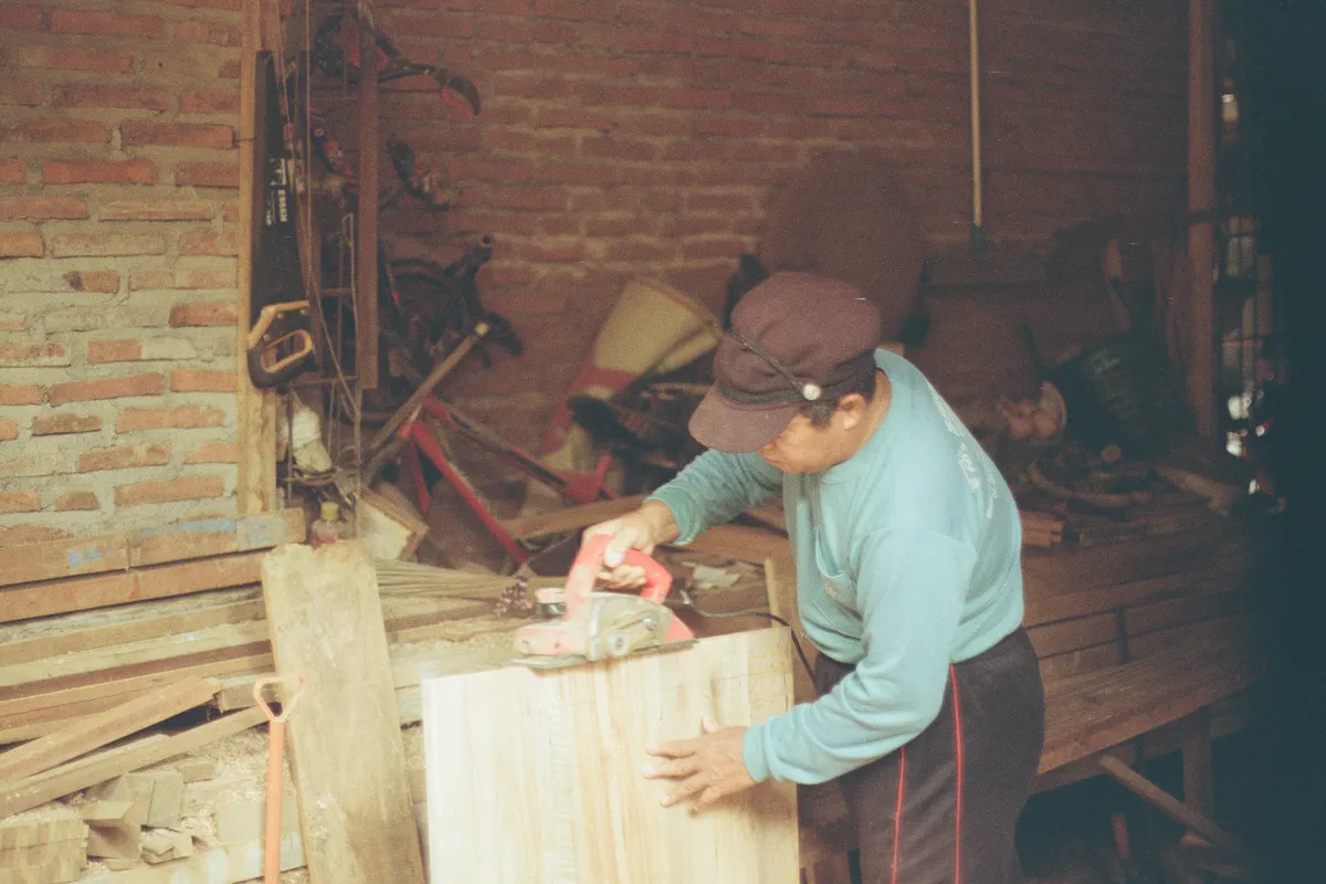 Carpintero lijando un panel de madera en un taller rústico