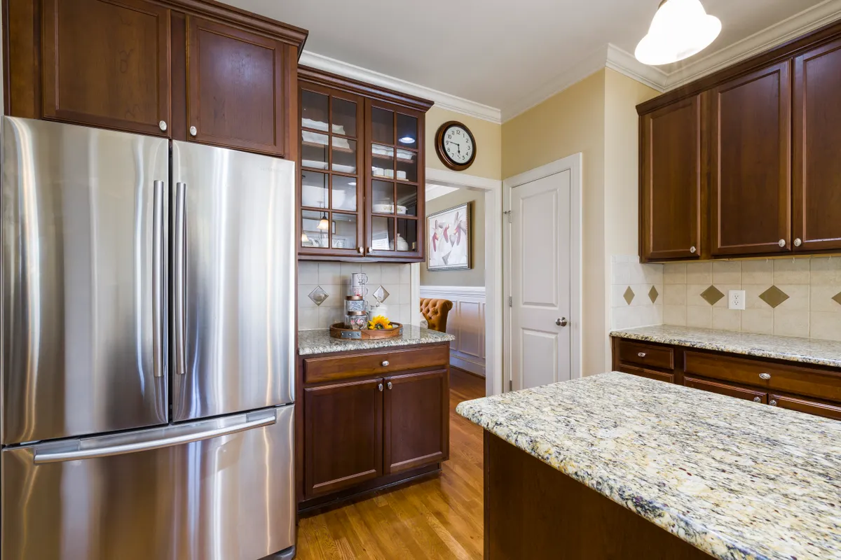 Cocina amplia con electrodomésticos de acero, muebles de madera y granito