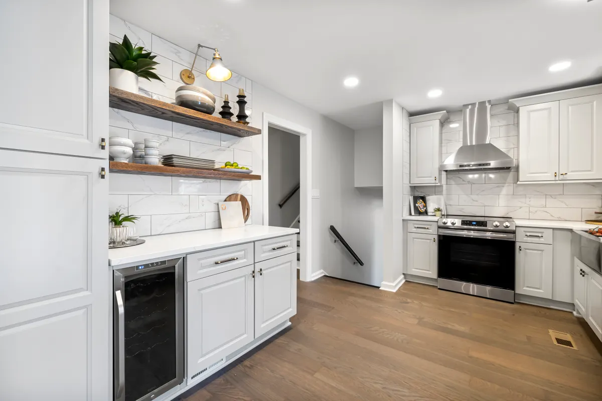 Cocina blanca con una vinoteca de puerta de cristal integrada bajo la encimera