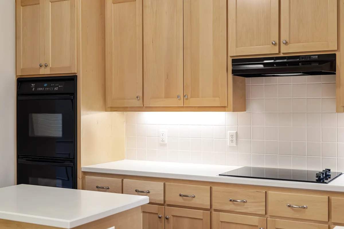 Cocina con muebles de madera, horno negro y placa de inducción