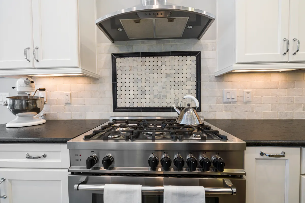 Cocina contemporánea con fogones de acero inoxidable, un hervidor y muebles lisos