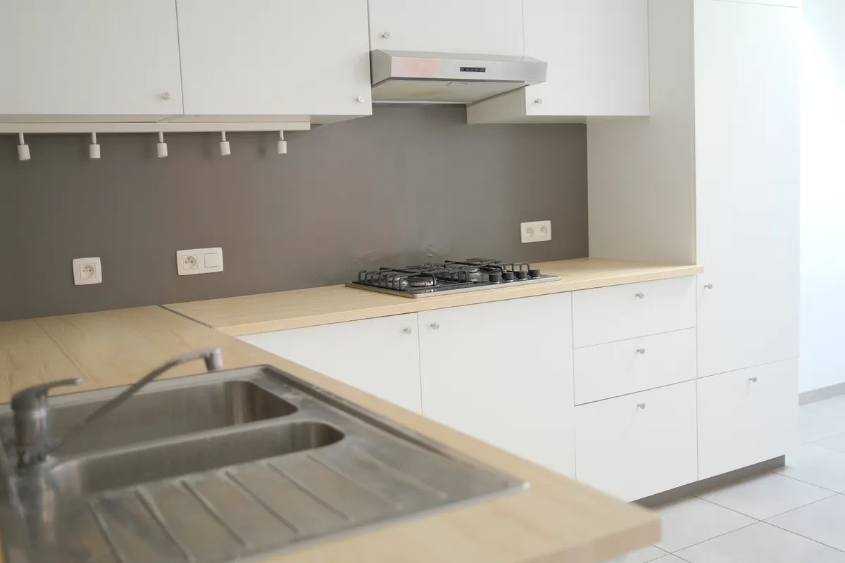 Cocina minimalista con encimera de madera, fregadero de acero inoxidable y placa de gas