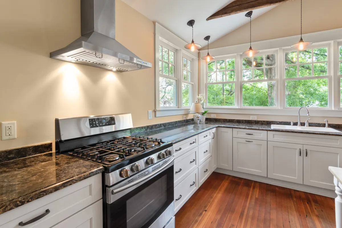 Cocina moderna y luminosa con fogones de gas, muebles blancos y luz natural