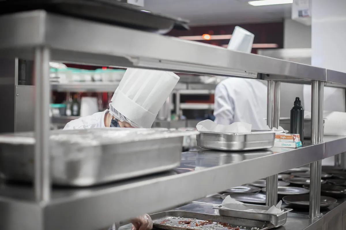 Cocineros trabajando tras estanterías de acero inoxidable en una cocina profesional