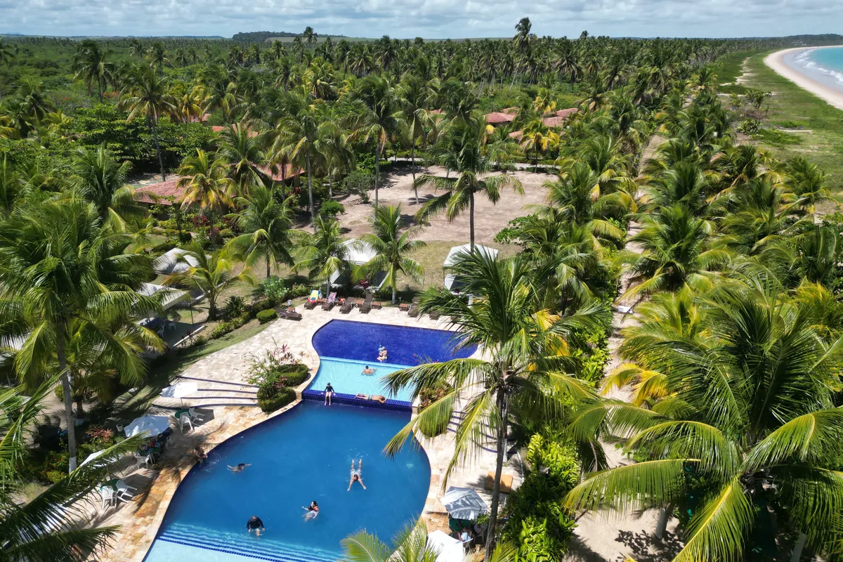 Complejo con piscina, jardines y vegetación junto a la costa