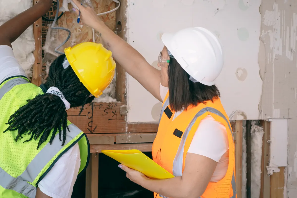 Dos ingenieras con equipo de seguridad inspeccionando un cableado