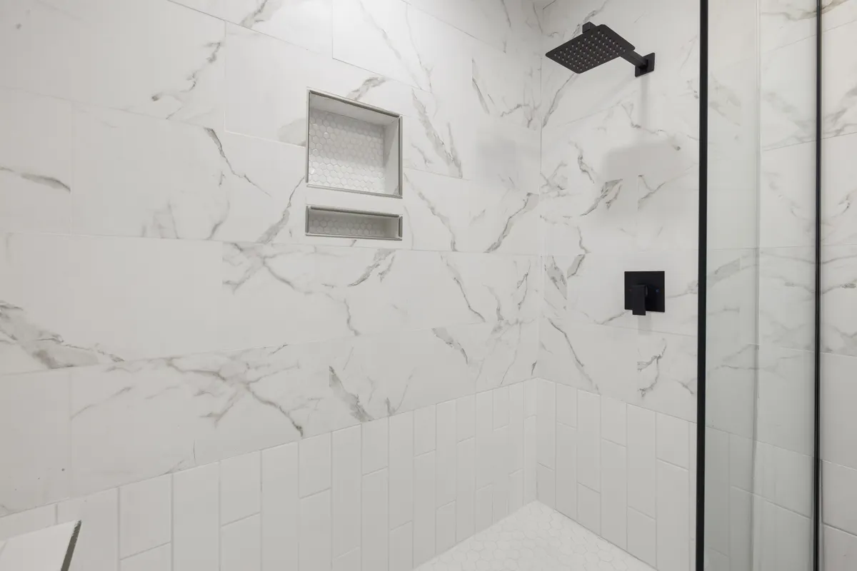 Ducha con revestimiento de mármol y grifería negra