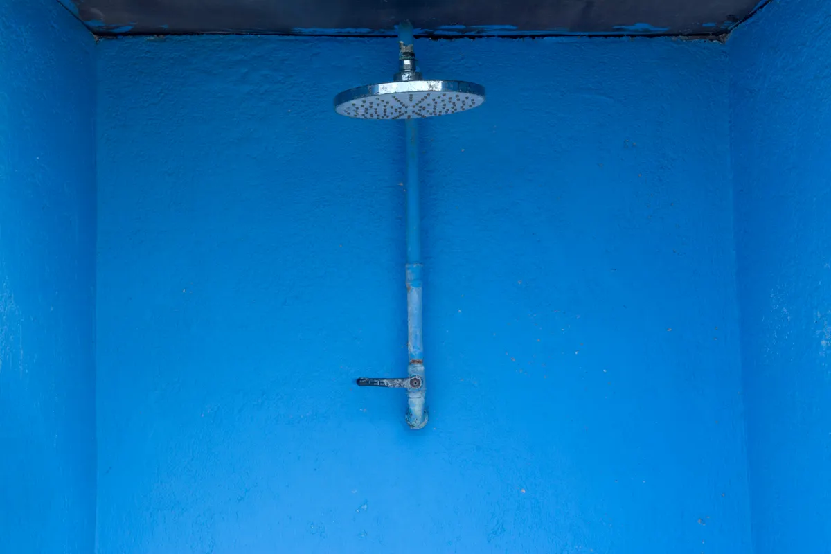 Ducha de pared azul texturizada con un rociador de lluvia metálico