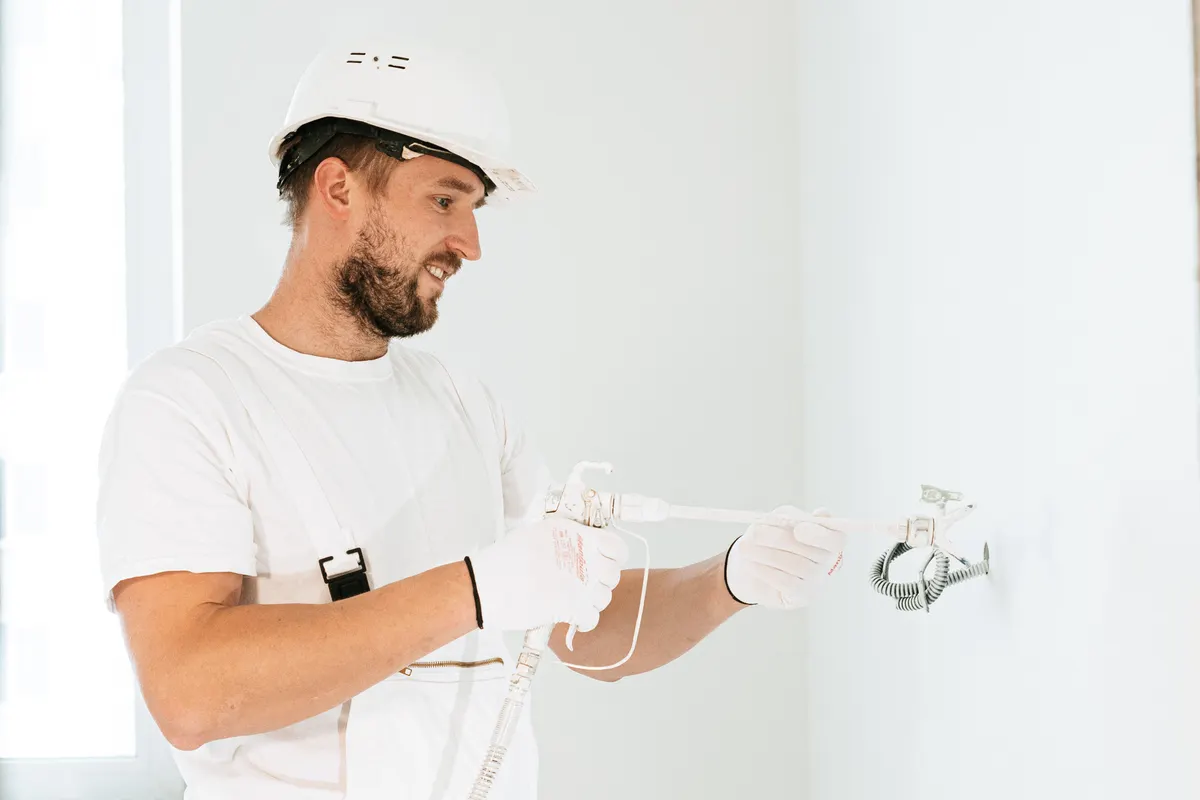 Electricista con equipo de seguridad instalando cableado en un edificio de obra nueva