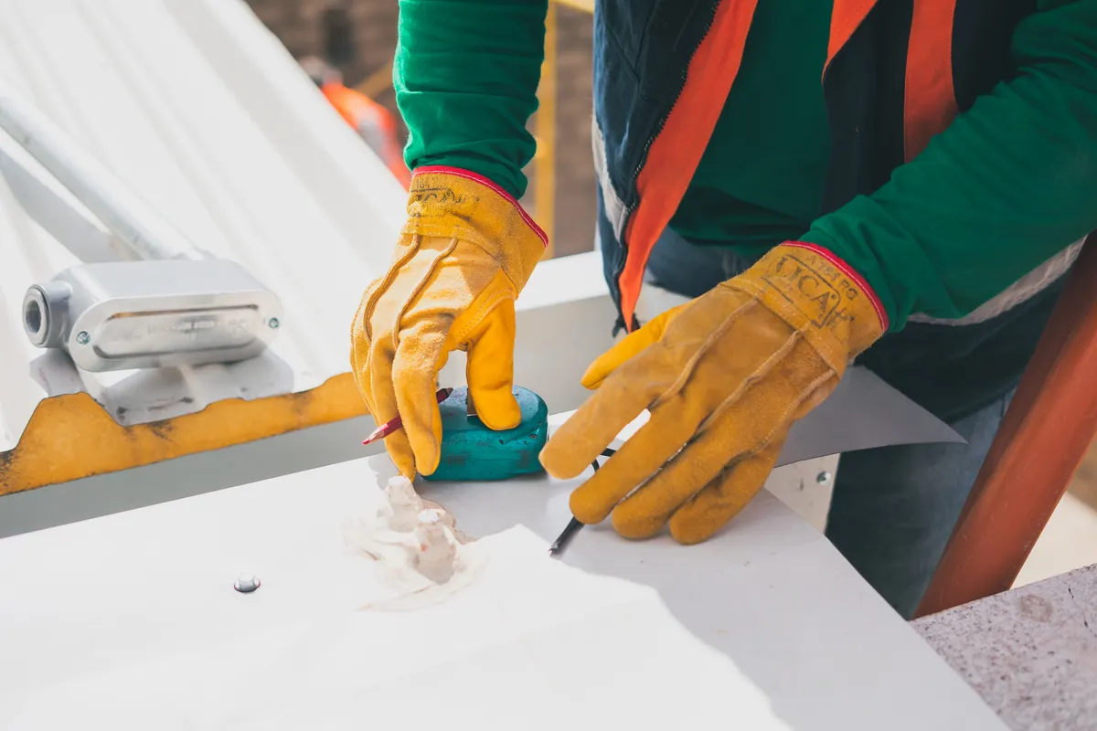 Electricista con guantes de protección tomando medidas en un tejado a plena luz del día
