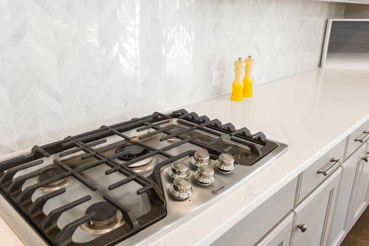 Encimera con cocina de gas, azulejos blancos y un salero y un pimentero amarillos