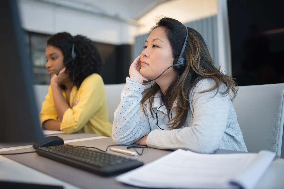 Equipo de atención al cliente con auriculares trabajando concentrado en sus mesas