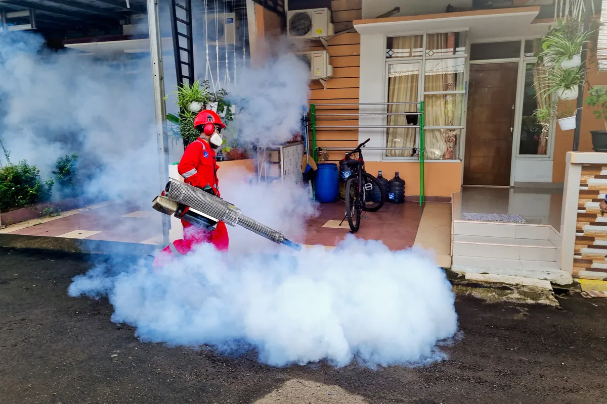 Especialista en plagas fumigando con una máquina de humo el exterior de una casa