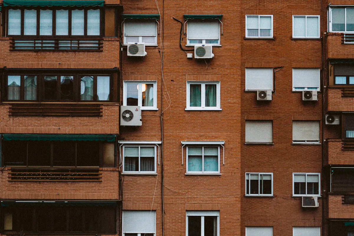 Fachada de ladrillo naranja de un bloque de pisos con ventanas y aires acondicionados