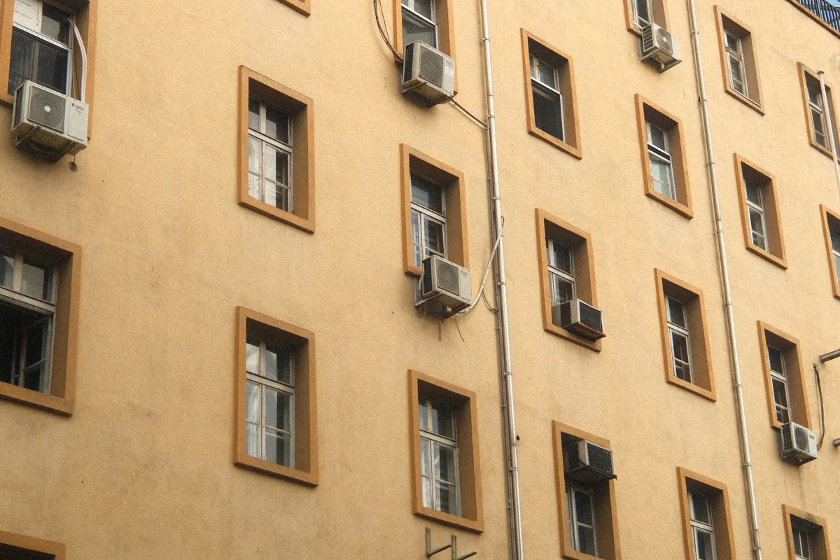 Fachada de un edificio urbano con aires acondicionados y ventanas en un día soleado