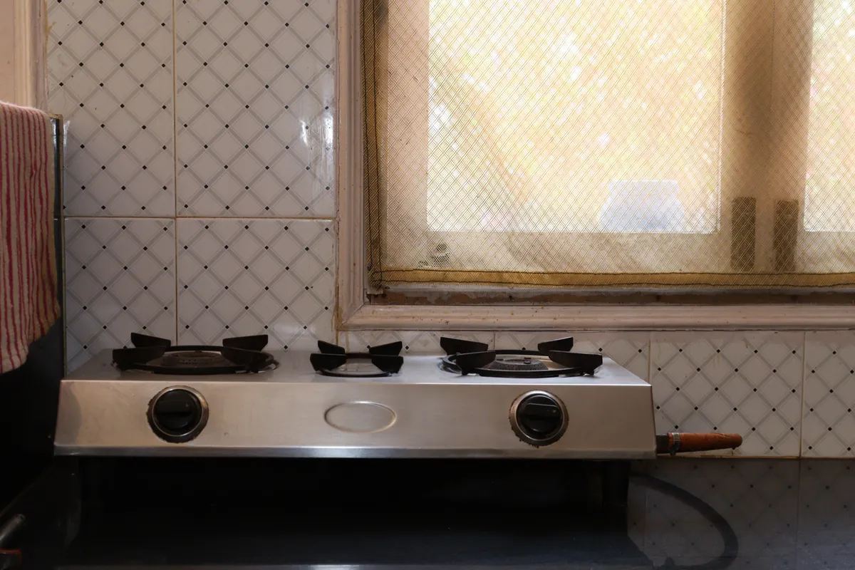 Fogones de acero inoxidable en una cocina doméstica con pared alicatada y ventana