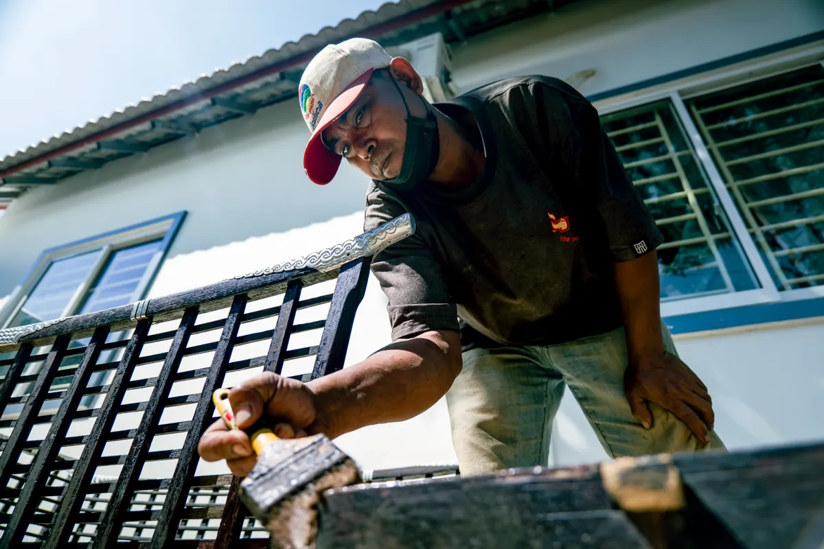 Hombre con gorra pintando una estructura metálica al aire libre