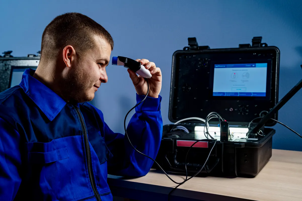 Hombre con uniforme azul usando un equipo de diagnóstico avanzado en un taller
