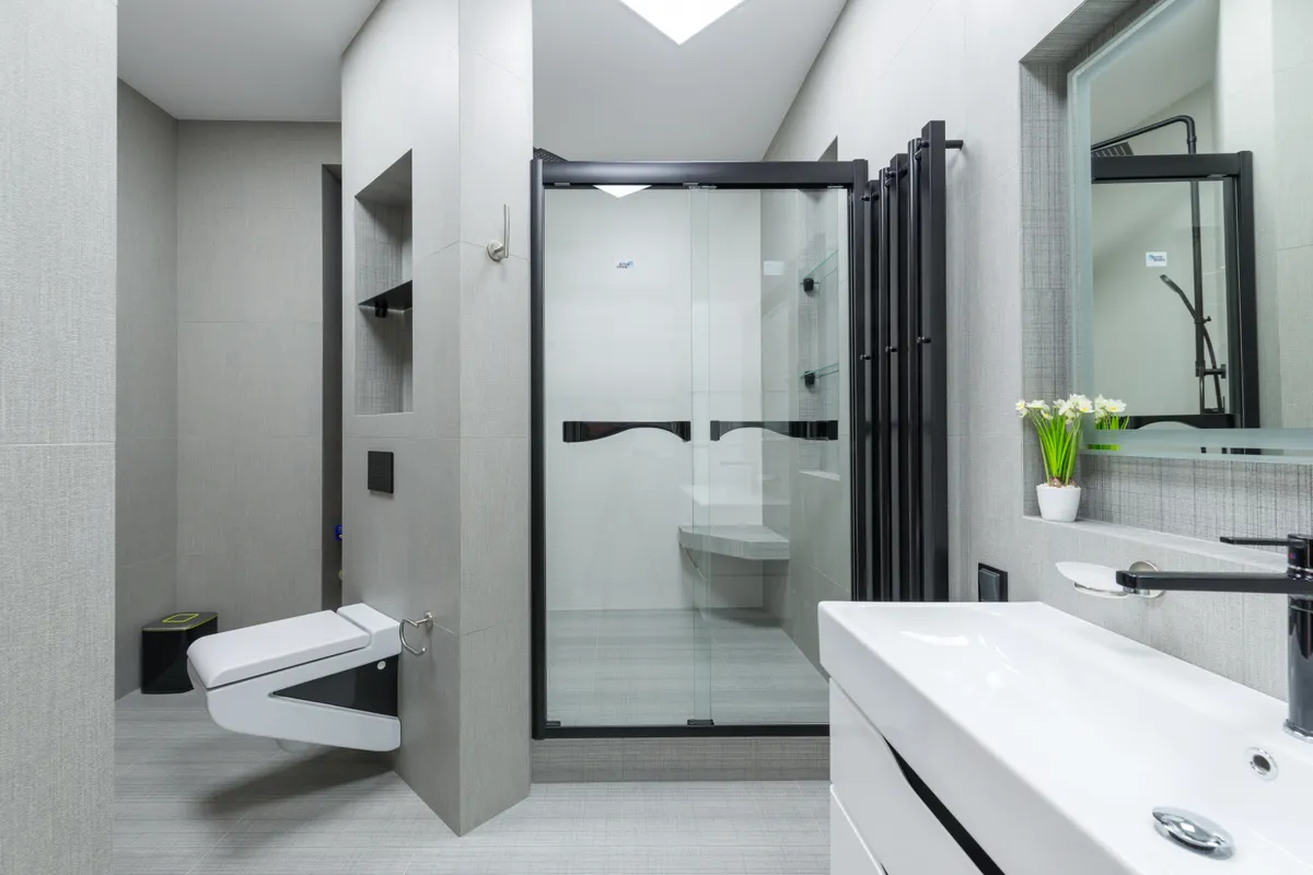 Lavabo con grifo y espejo en un baño claro con inodoro y cabina de ducha