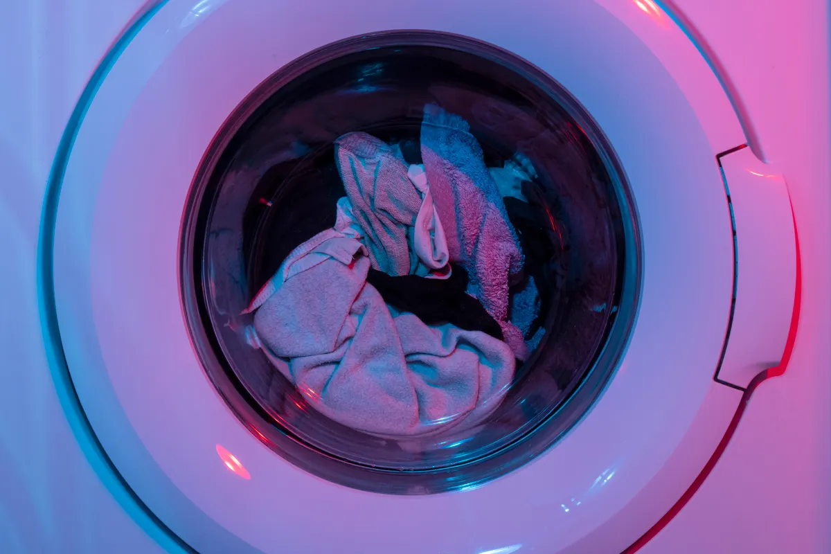 Lavadora de colores con ropa dentro bajo intensas luces moradas y azules