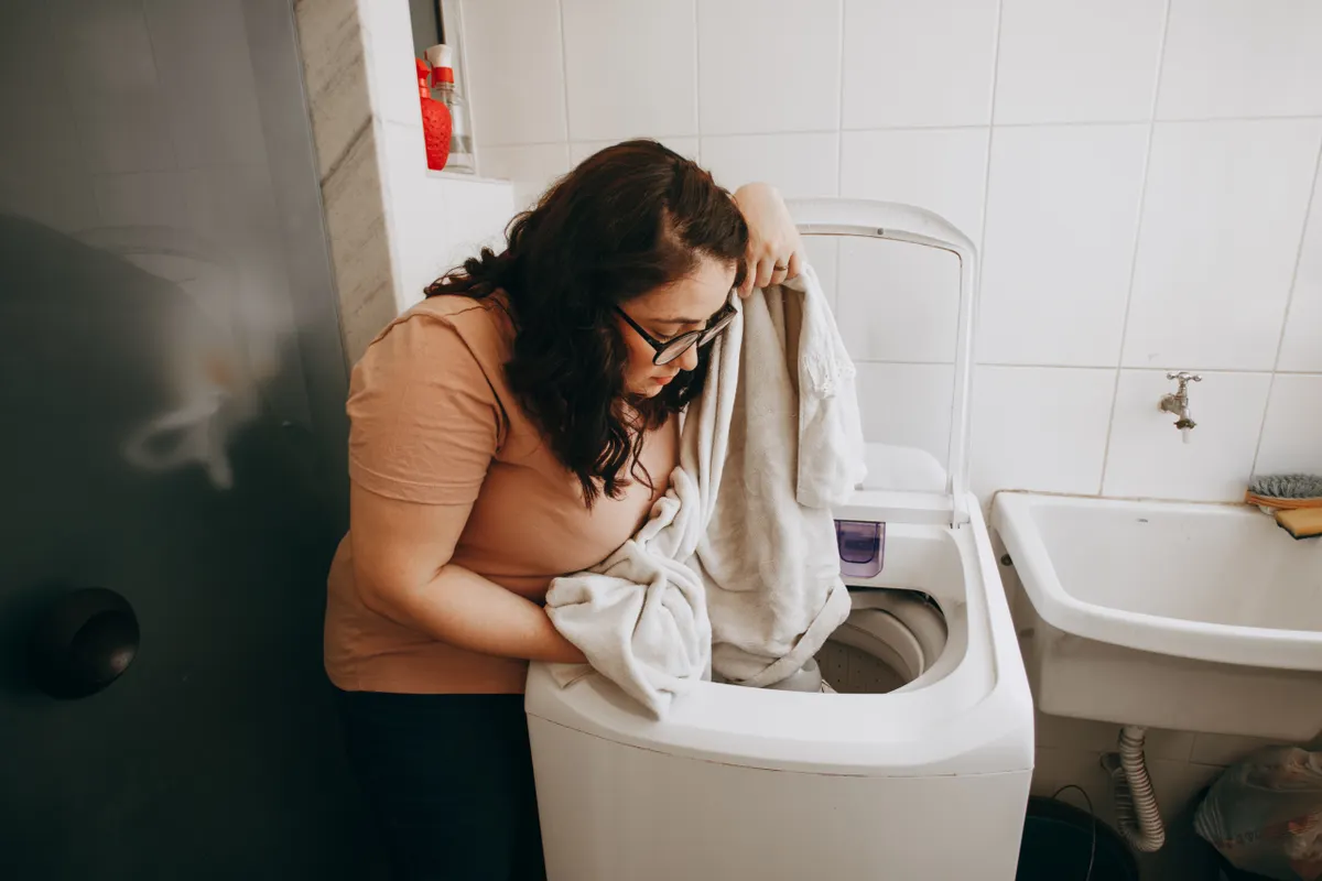 Mujer cargando la ropa en una lavadora en un lavadero moderno