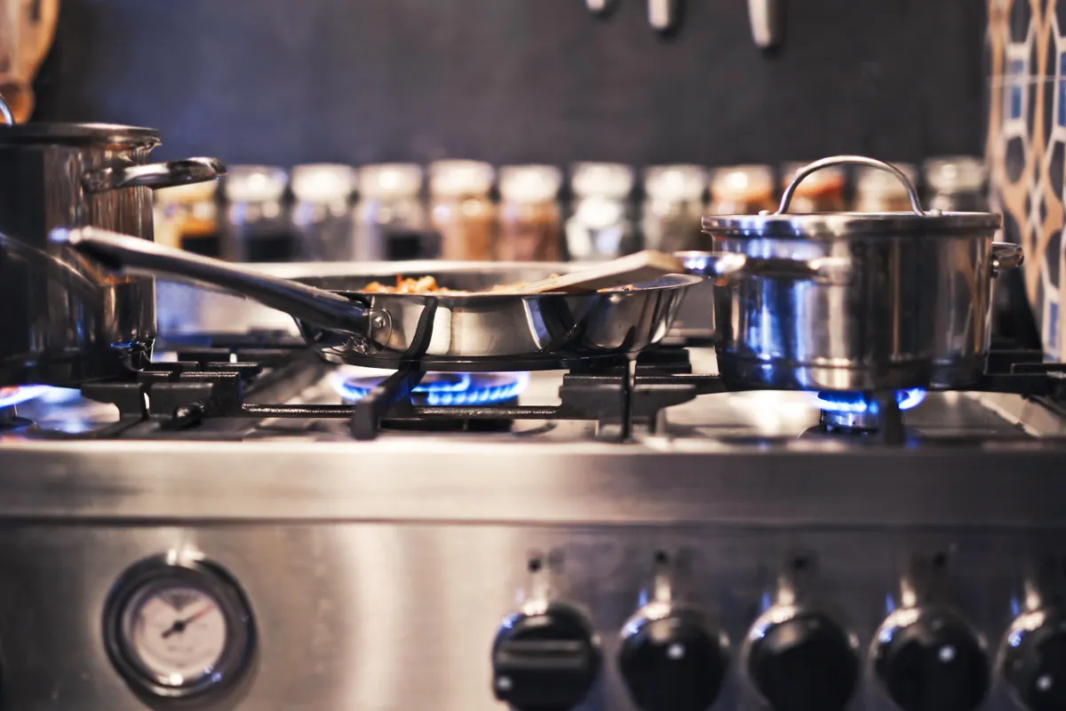 Ollas y sartenes sobre una cocina de gas con las llamas azules encendidas