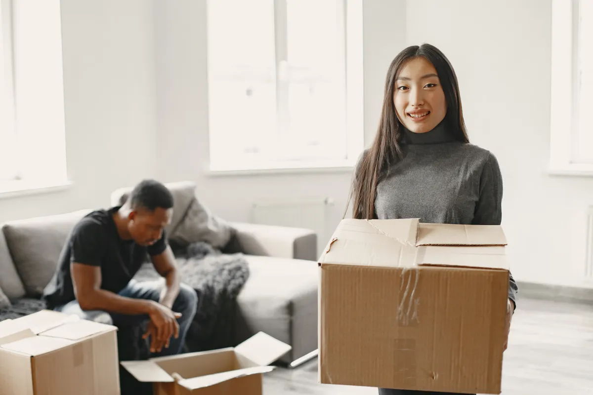 Pareja contenta desembalando cajas de mudanza en su nuevo piso