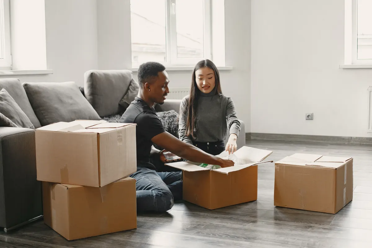 Pareja feliz sacando cosas de las cajas de mudanza en el salón de su nuevo piso