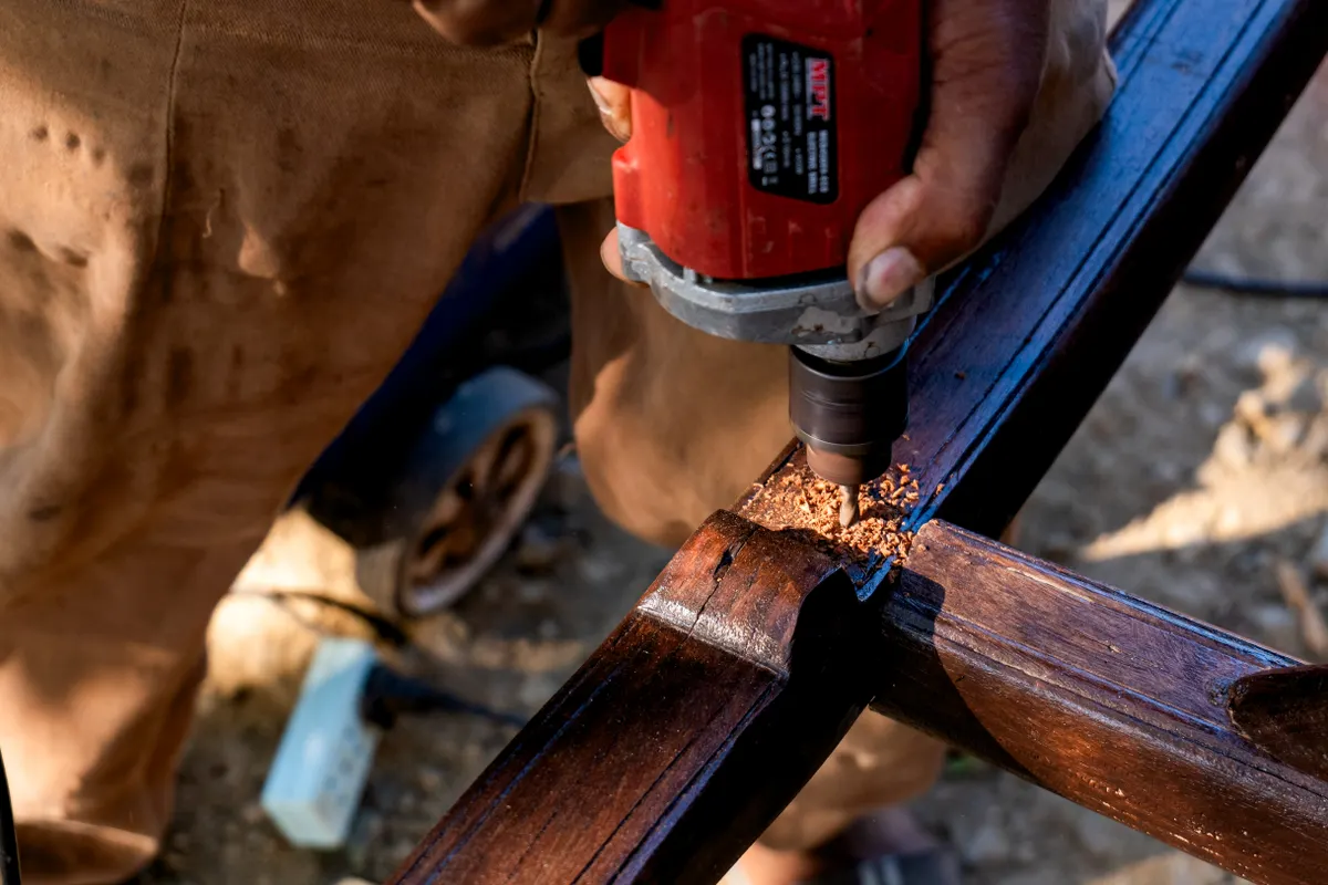 Persona taladrando una viga de madera al aire libre en primer plano