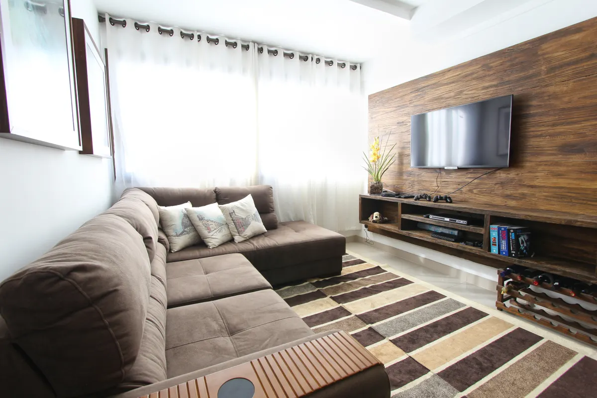 Salón moderno con sofá marrón y televisor colgado en la pared